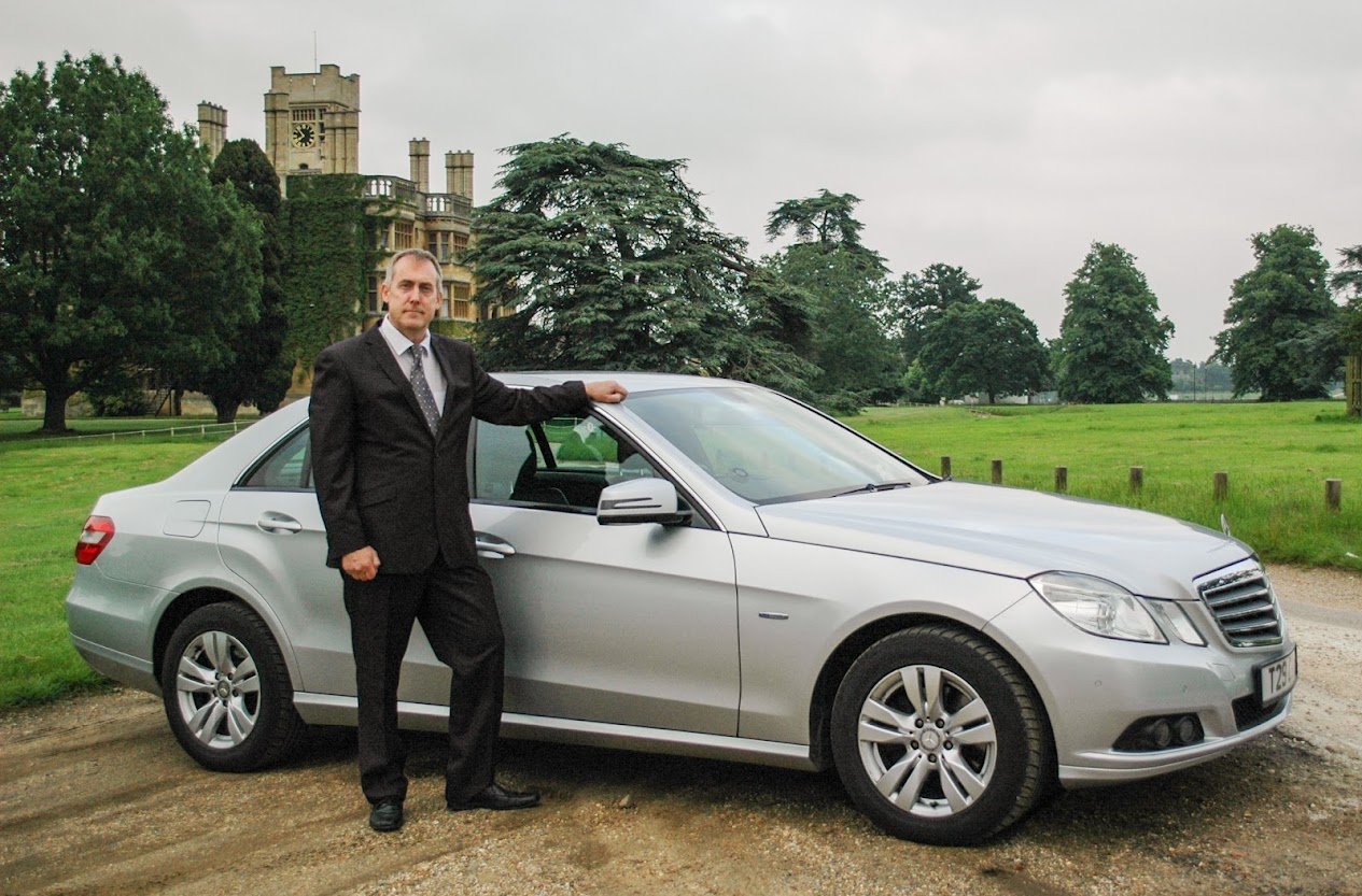 Ivars, co-founder and driver, beside the silver Mercedes E-Class taxi